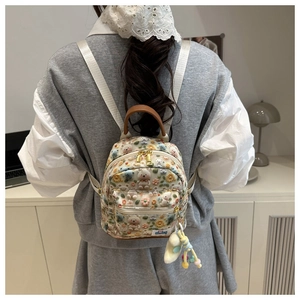 Detailed close-up of cartoon backpack with 3D floral bear patterns and plush charm accessory