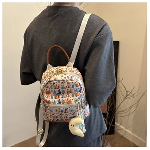 Detail of cute forest fox print mini backpack featuring a plush yellow moon pendant