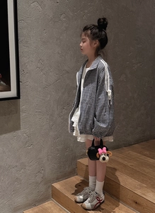 Dettaglio mini borsa per bambina con ciondolo a cucciolo rosa e giacca a quadretti alla moda