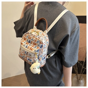 Detail view of mini backpack with cartoon forest animal print and yellow moon plush charm