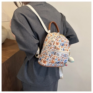 Detail view of mini cartoon backpack with forest prints and plush pendant on model