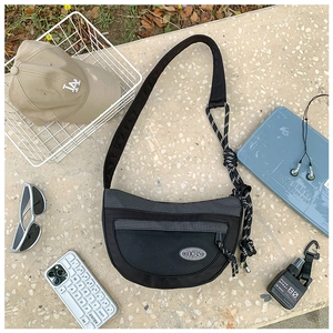 Détail du sac à bandoulière en maille noire avec large sangle et nœuds décoratifs