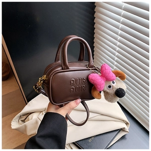 Dettaglio mini borsa in pelle marrone con goffratura AMIR e ciondolo a forma di cane