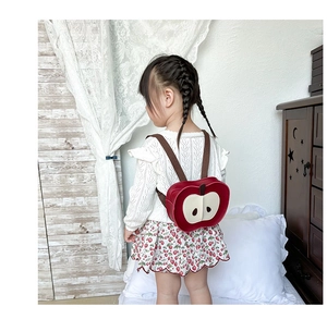 Vista posteriore di un bambino con zainetto a forma di mela rossa e spalline marroni