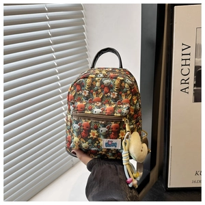 Detail of cute cartoon mini backpack featuring a bear patch and soft yellow charm