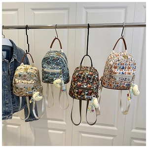 Detail showing four mini cartoon backpacks with embroidery and plush pendants