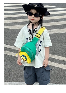 Close-up of a green cartoon car crossbody bag worn by a child on a street background