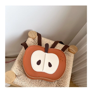 Dettaglio dello zaino per bambini a forma di mela in ecopelle marrone arancio su sgabello