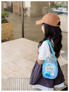 Outdoor shot of a blue Elsa and Olaf sequin crossbody bag worn by a young child