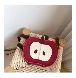 Dettaglio dello zaino per bambini a forma di mela rossa su uno sgabello intrecciato