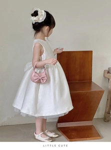 Toddler girl in white satin dress holding a mini pink handbag with bow detail