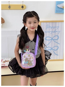 Detail of purple cartoon shoulder bag with sequins, crown decor, and colorful pompoms