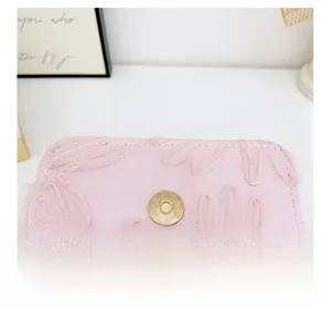 Detail of pink lace embroidery floral pattern with a round gold metal magnetic clasp