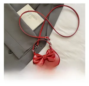 Detail of red PU leather mini handbag with a large decorative bow and silver metal clasp