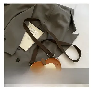 Detail view of apple-shaped kid's crossbody bag in brown and cream synthetic leather