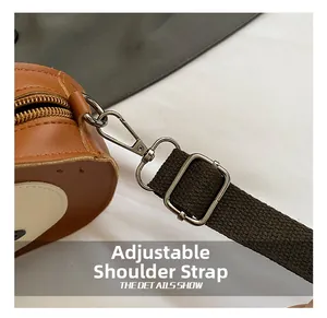 Detail view of adjustable strap with metal D-ring and hook on brown leather bag
