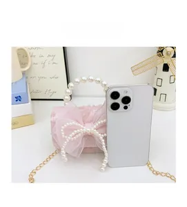 Mini pink lace bag with pearl handle and bow shown next to a smartphone for scale