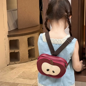 Detail of a toddler wearing the red apple shaped backpack with adjustable brown straps