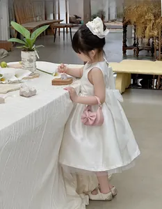 Close-up of a pink mini handbag with a bow detail, paired with a white dress for kids