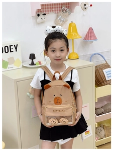 Detail of cute khaki capybara kids backpack with a transparent window and plush charms