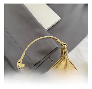 Détails du mini sac à main doré brillant avec surpiqûres précises et anneau en métal chic