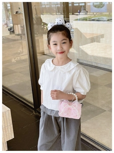 Pink girl's small handbag with pearl handle and bow, styled with a casual kids' outfit