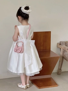 Detailed back view of a pink bow mini handbag styled with a white girls party dress