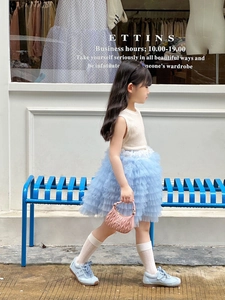Detail of girls knit vest and layered blue tulle skirt set in a chic outdoor setting
