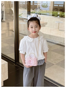 Pink girls crossbody bag with large mesh bow and pearl handle shown on a child model