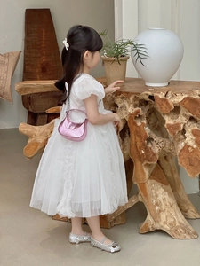 Détail du sac à chaîne rose métallisé assorti à une robe en tulle blanche pour filles