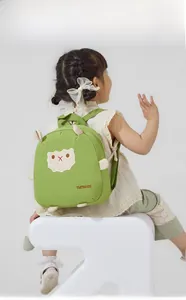 Détail de la broderie alpaga blanc sur sac à dos vert pour enfant avec logo TMTBAGS