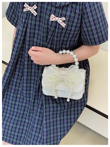 Detail of white sequin kids handbag with tulle bow and elegant pearl handle strap