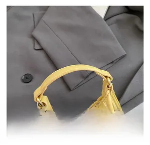 Macro detail of creamy yellow pleated handbag showing soft texture and gold metal hardware