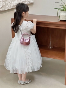 Détail d'un mini sac hobo rose métallisé assorti à une robe en dentelle blanche