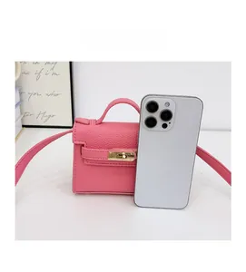Mini pink textured leather kids shoulder bag with gold clasp shown next to a smartphone