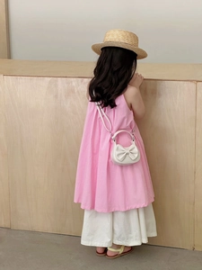 Close-up of white leather girl handbag with large bow and pink summer dress outfit