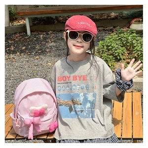 Outdoor lifestyle view of kids pink plaid backpack with bow and casual graphic t-shirt