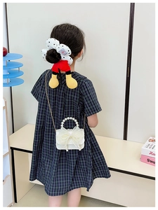 Detailed back view of girl carrying white mesh crossbody bag with pearls and bow