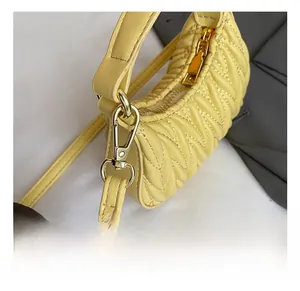 Detail of metal hook and zipper on yellow quilted pleated mini handbag for girls