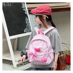 Detail of pink gingham kids backpack with decorative 3D bows and soft plush textures
