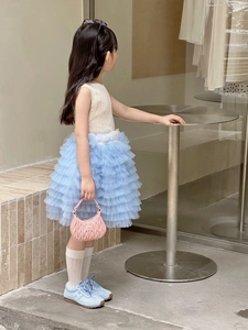 Detail of girl's pink quilted handbag and layered lace tulle cake skirt in outdoor set
