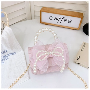 Detailed view of lace handbag with large mesh bow and pearl handle on a magazine table