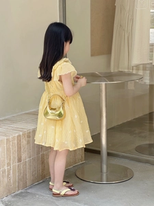 Détails d'une robe d'été jaune avec manches à volants et broderies florales