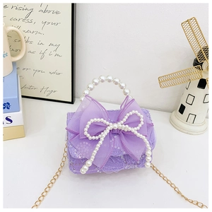 Detail view of purple mini kids handbag with lace fabric, pearl handle and bow
