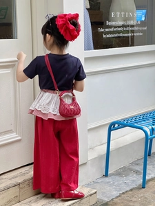 Outdoor street fashion shot of a red quilted leather shoulder bag for young girls