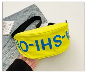 Detail showing bright yellow kids crossbody bag with large blue letter print and strap