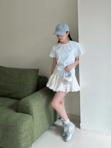 Détail d'un mini sac à main argenté scintillant avec un t-shirt bleu clair uni