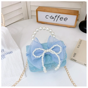 Detail of light blue girls handbag with lace, sequins, large bow and pearl handle