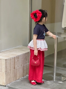 Detail of a navy cartoon T-shirt and red wide-leg trousers with lace ruffles for girls