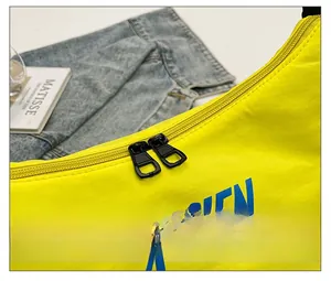 Detail showing smooth black metal double zippers on bright yellow nylon crossbody bag